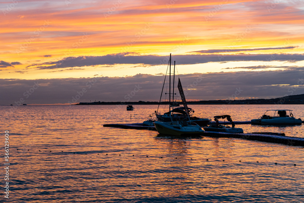 Crimson sunset in Gelendzhik bay. Evening calm. Pleasure yachts on pier in rays of evening sun. multi-colored rays of setting sun are reflected in sea water. Gelendzhik, Russia - September 20, 2022 Crimson sunset in Gelendzhik bay. Evening calm. Pleasure yachts on pier in rays of evening sun. multi-colored rays of setting sun are reflected in sea water. Gelendzhik, Russia - September 20, 2022