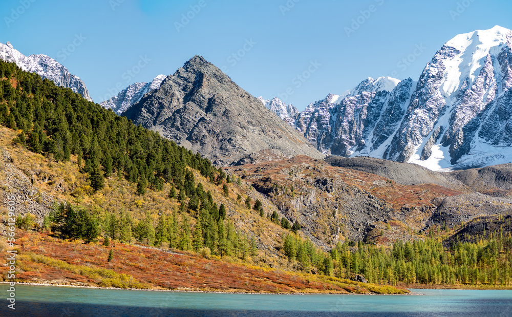 Panorama of Lake Shavlinskoye with a pyramid-like mountain against the background of rocks with tongues, glaciers and snow in Altai. Peaks Dream, Fairy Tale and Beauty.