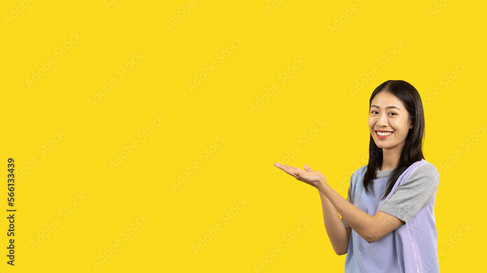 Asian woman with holding copyspace imaginary on the palm to insert an ad, Showing copyspace pointing, Showing her hand to present something on yellow background. Asian woman with holding copyspace imaginary on the palm to insert an ad, Showing copyspace pointing, Showing her hand to present something on yellow background.