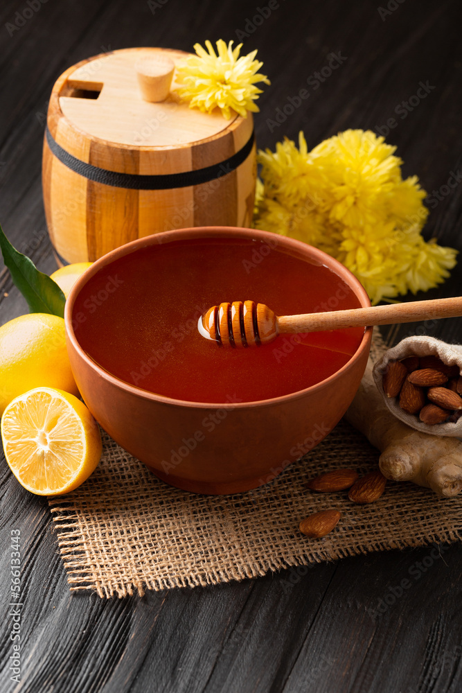 Clay bowl with honey and a wooden barrel for honey on a wooden background. Close-up. Clay bowl with honey and a wooden barrel for honey on a wooden background. Close-up.