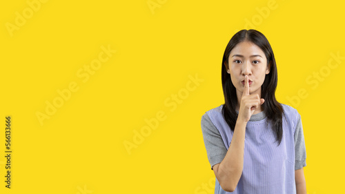 Bilde på lerret Asian woman doing silent gesture with finger, Noiseless symbol, Noisy mall, Hide a secret, Do not speak