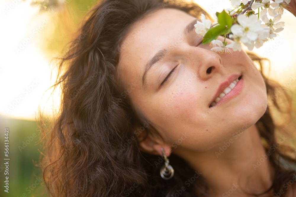 A young brunette girl poses with a blossoming cherry branch A young brunette girl poses with a blossoming cherry branch