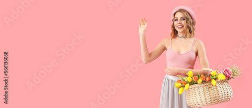 Beautiful happy young woman with basket of flowers on pink background with space for text