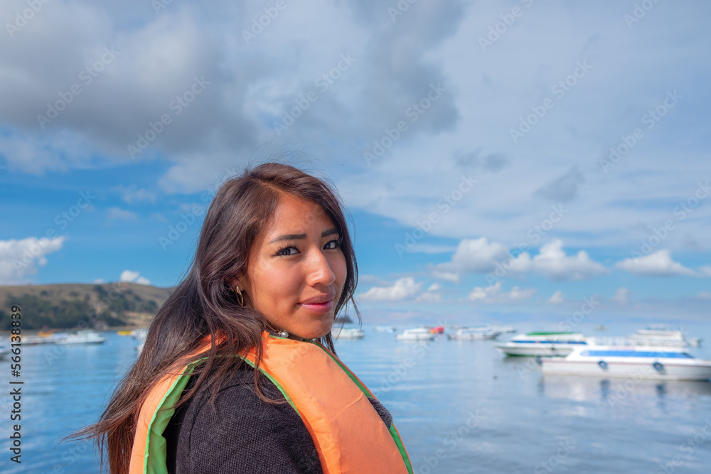 Fototapeta premium smiling young latin woman sightseeing in a boat on the shores of lake titicaca in bolivia