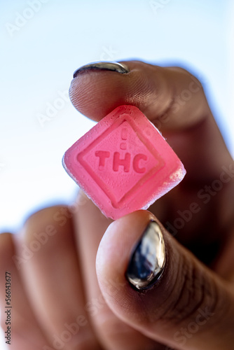 Female model holding a thc edible between her fingers