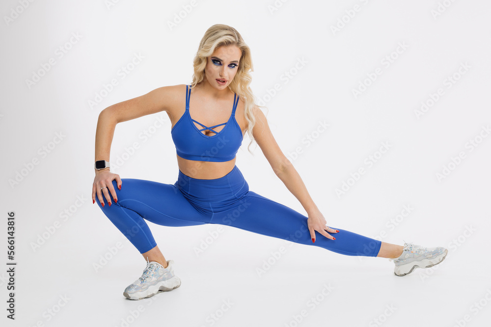 A young woman squats on a white background. Stretching before training. Fitness instructor A young woman squats on a white background. Stretching before training. Fitness instructor