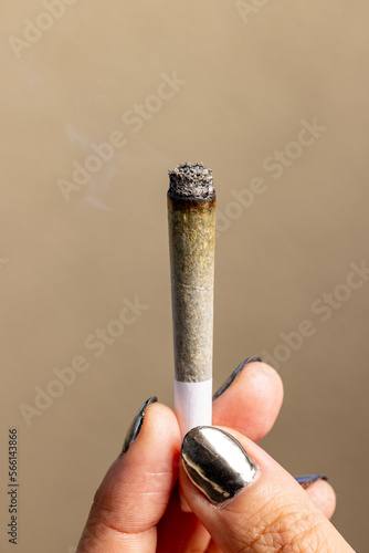 Female model holding a lit joint upright