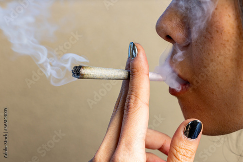 Female model smoking a lit joint with smoke all around