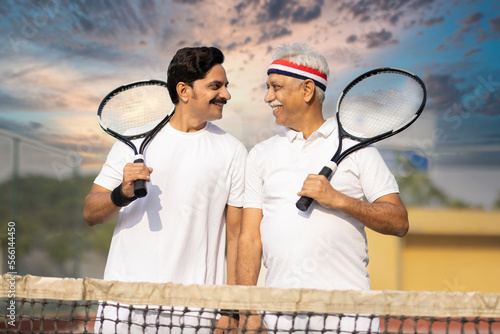 Photography senior man playing tennis with his son.