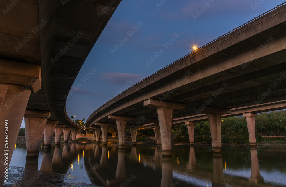 Underside of an elevated road across river at dusk