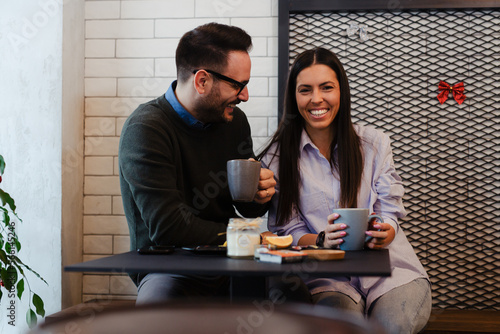 Happy couple drinking coffee in cafe. Smiling man and woman having breakfast together.
