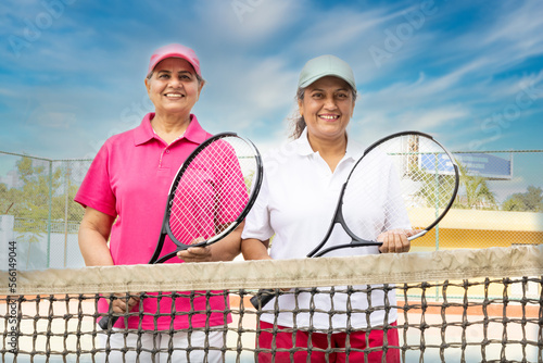 Older women with tennis rackets on court. © G-images