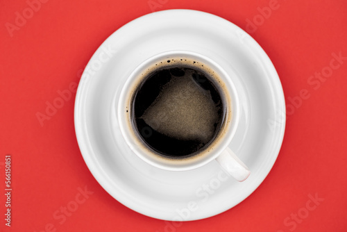 Coffee cup and saucer on red background, flat lay.