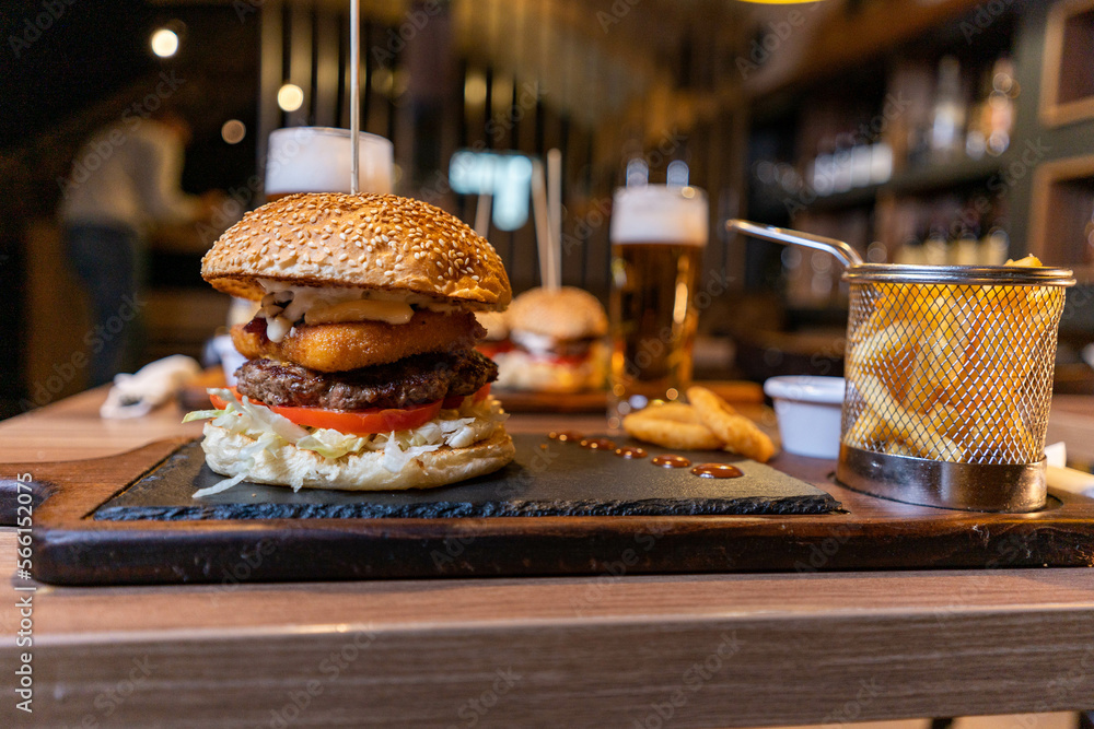 Delicious homemade hamburger and beer, onion ring and french fries on the table on wooden background.