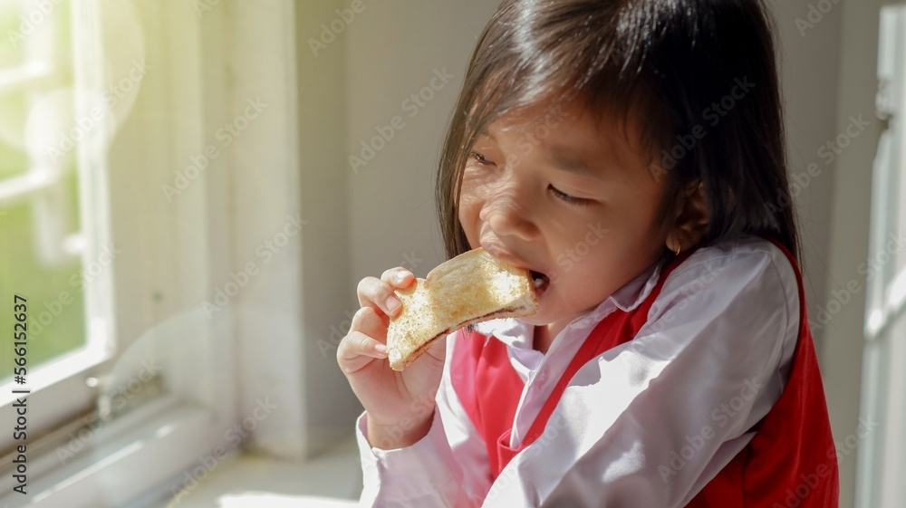 little asian girl wearing school uniform eating bread on window seat little asian girl wearing school uniform eating bread on window seat