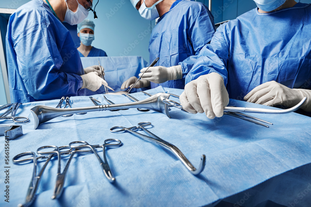 Surgical Team. Surgical nurse giving surgical scissors to male surgeon during operation in operating theatre - obrazy, fototapety, plakaty 