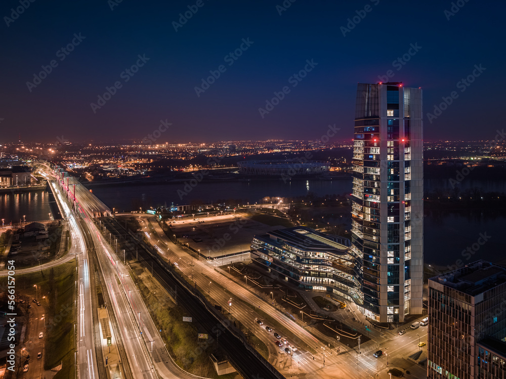 Budapest, Hungary - Aerial view of Budapest's new, illuminated MOL Campus skyscraper building with Rakoczi bridge above River Danube and city skyline at background at dusk with dark blue sky