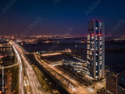 Budapest, Hungary - Aerial view of Budapest's new, illuminated MOL Campus skyscraper building with Rakoczi bridge above River Danube and city skyline at background at dusk with dark blue sky © zgphotography