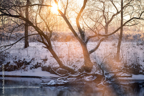 Obraz na płótnie Early spring. Landscape of river and woodland on froze morning. Sunbeams beat through tree branches. w salonie