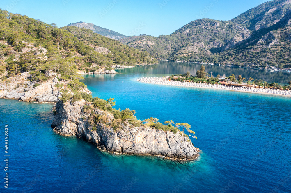 Turkey, scenic beach with white sand surrounded blue sea. Amazing aerial view on sea coast. Blue lagoon lost surrounded between high moutains. Sunny day in small town Oludeniz, Turkey.