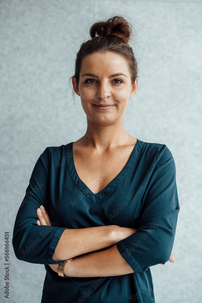 Smiling businesswoman with arms crossed in front of wall Smiling businesswoman with arms crossed in front of wall