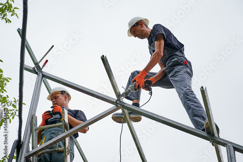 Workers installing metal beams for solar panels. Concept of renewable and ecological energy. Modern technology and innovation. Idea of environment safe. Men wearing workwear and working gloves