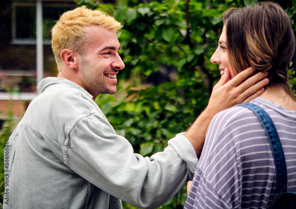 Happy boyfriend touching cheek of girlfriend in back yard