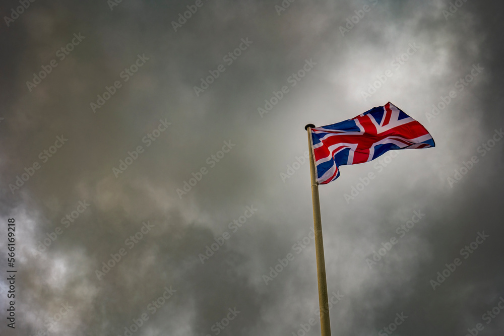 Union Jack flag waving below storm clouds