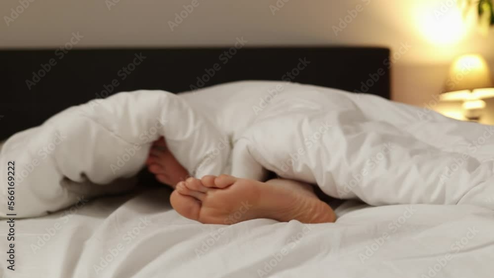 Woman is sleeping in bed. Close-up of feet sticking out from under blanket. Concept of recreation. Woman is sleeping in bed. Close-up of feet sticking out from under blanket. Concept of recreation.