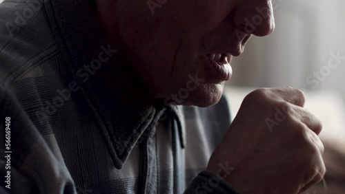 Caucasian pensioner coughing into his fist while at home. selective focus.illness and cough, asthmatic elderly man, throat disease in an old man.Coronavirus in pensioners