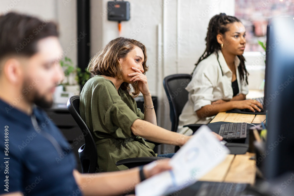 Stressed businesswoman sitting in front of desktop PC at office Stressed businesswoman sitting in front of desktop PC at office
