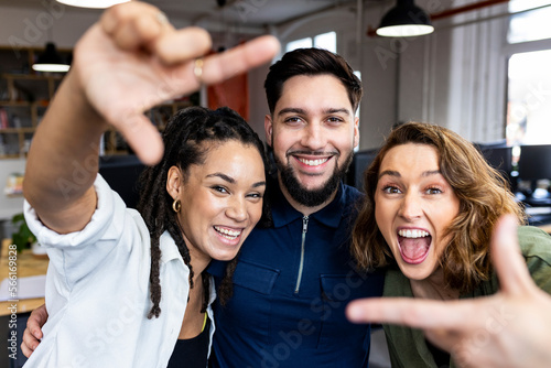 Happy business people making finger frame in office