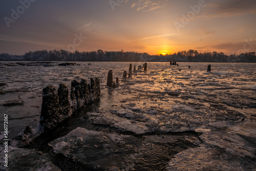 Remains of an old pier over a frozen river during a beautiful sunrise