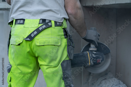 Closeup view of Workers hands holding angle grinder and cutting beton.