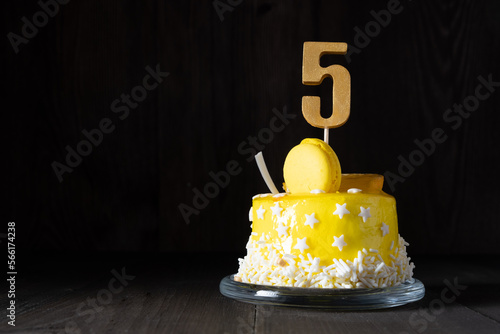 The number Five on a yellow cake for an anniversary or birthday in a dark key. photo