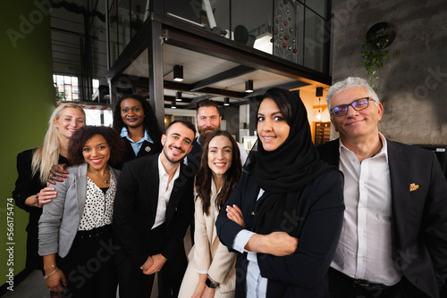 Portrait of large group of work with diverse ethnicity and age looking at camera smiling.
