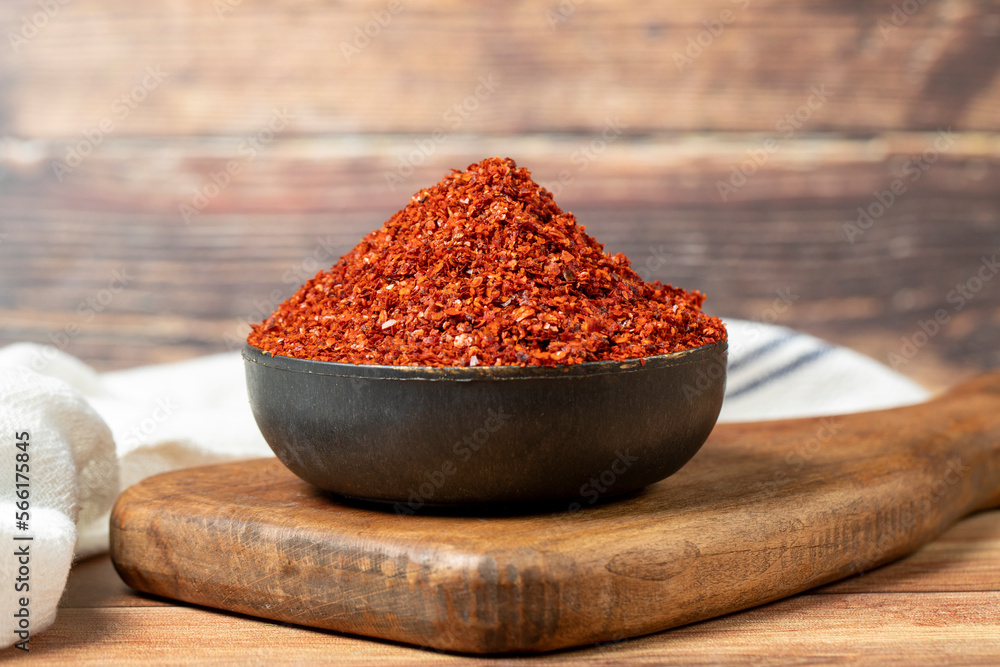 Red pepper flakes. Crushed chili pepper in bowl, dried chili flakes on  wooden background. Close up Stock Photo