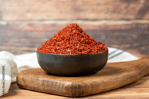 Red pepper flakes. Crushed chili pepper in bowl, dried chili flakes on wooden background. Close up