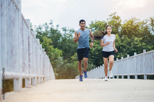 Young couple running together on road across the bridge. Couple  fit runners fitness runners during outdoor workout.