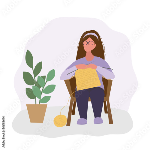 The girl sits in a chair and knits. A needlewoman at work. Hobby and leisure
