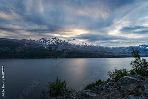 Norwegian fjord from a view point high above the fjord with snowcapped mountains and nice clouds in the night sky © Jens