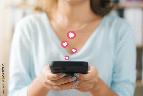Valentine's day and love day concept, woman finger touching heart icon on screen in smartphone application, happy woman posting love heart emoji icon button, search app Online couple.