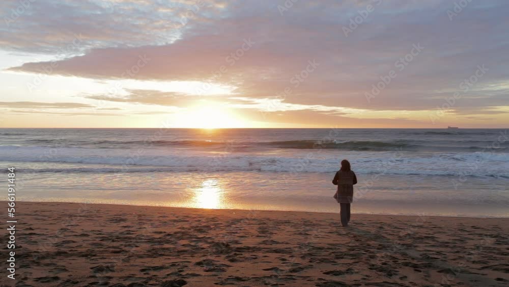 A woman approaches the seashore and looks at the sunset. A woman approaches the seashore and looks at the sunset.