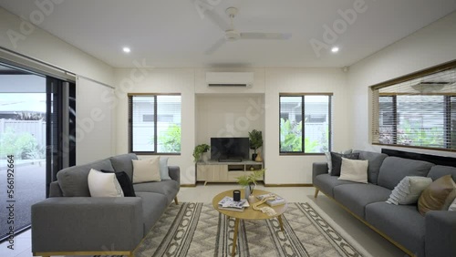 Contemporary open plan living room. White finishes in a white house. Clean crisp home. Styled with TV units, couches, tables and rug. Sliding door to outdoor area. Modern split system aircon