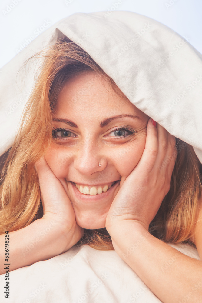 Conceptual image: good happy morning. Young girl lying in bed under the blanket in the morning Vertical image. Conceptual image: good happy morning. Young girl lying in bed under the blanket in the morning Vertical image.