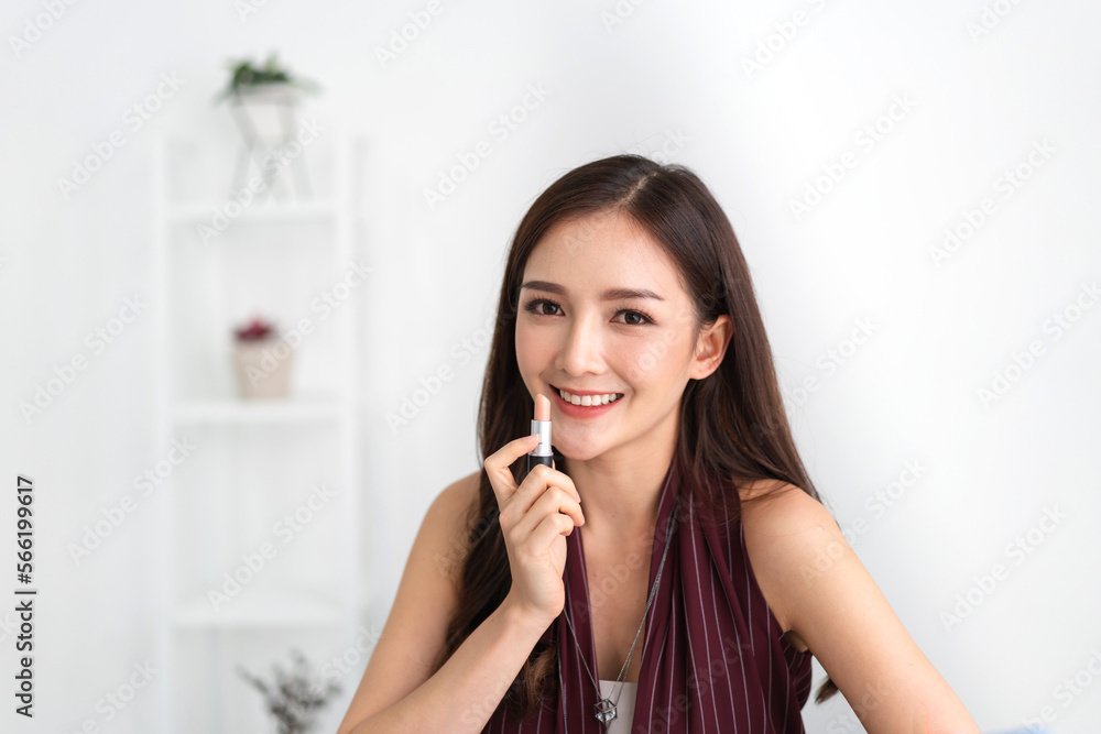 Smiling beautiful asian woman fresh healthy skin looking on mirror and enjoying applying skincare lips with red lipstick at home.facial beauty and cosmetic concept Smiling beautiful asian woman fresh healthy skin looking on mirror and enjoying applying skincare lips with red lipstick at home.facial beauty and cosmetic concept