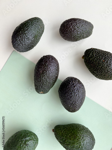 Many tasty ripe avocados on light green background, flat lay