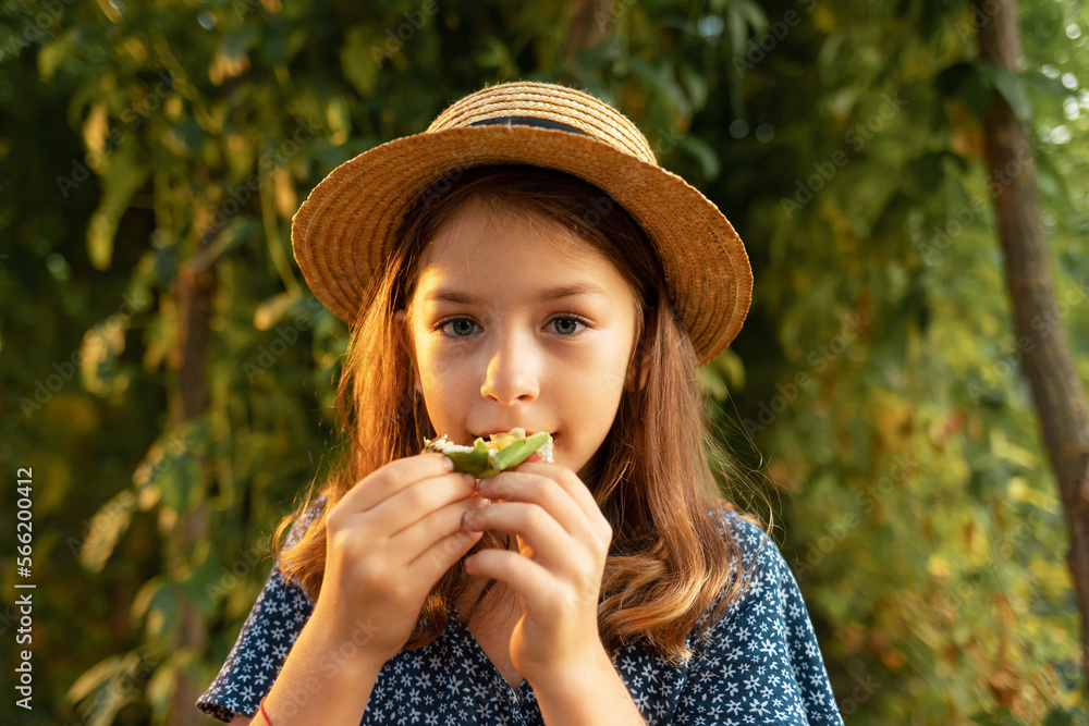 © _KUBE_ - Exotic fresh fruit. Close up portrait of cute little girl in a straw hat eating a passion fruit. Concept of organic gardening and home agriculture