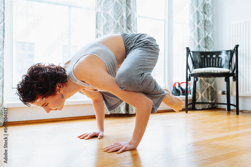 Muscular teenager girl, doing yoga in handstand, crow pose or bakasana. home workout