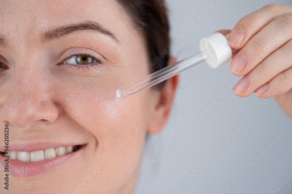 Caucasian woman uses blue anti-wrinkle face serum.